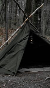 A primitive tent built with sticks and a tarp.
