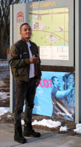Michael standing in front of a poster at Montgomery County Community College after being offered shelter by Opportunity House.